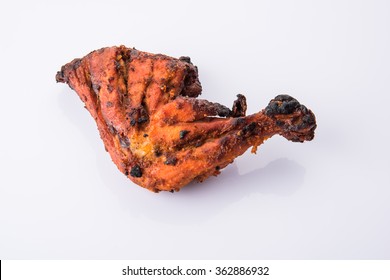 Tandoori chicken - prepared by roasting chicken marinated in yoghurt and spices in a tandoor. Big Leg piece kept isolated over white background. Selective focus