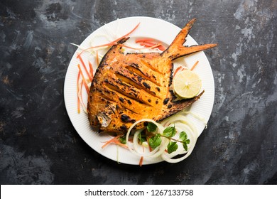 Tandoori Pomfret fish cooked in a clay oven and garnished with lemon , mint, cabbage and carrot salad. Selective focus
