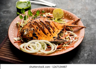 Tandoori Pomfret fish cooked in a clay oven and garnished with lemon , mint, cabbage and carrot salad. Selective focus