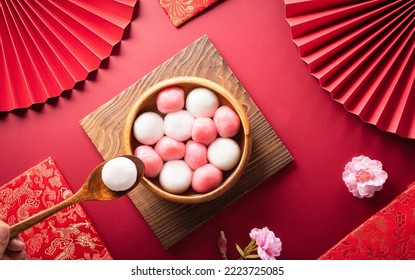 Tang Yuan(sweet dumplings balls), a traditional cuisine for Mid-autumn, Dongzhi (winter solstice ) and Chinese new year with plum flower and tea on red background. - Shutterstock ID 2223725085