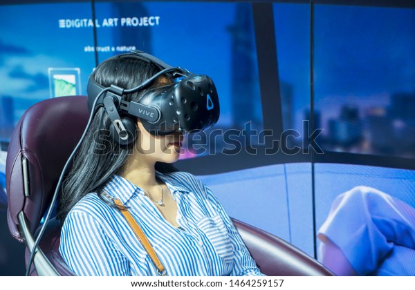 Tangerang -\
Indonesia. July 24, 2019: Young woman wearing a VR glasses and\
testing a driving simulator at event of Gaikindo Indonesia\
International Auto Show (GIIAS)\
2019