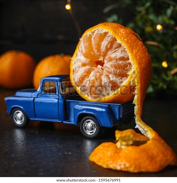 tangerine is transporting a toy car,\
new Year mood\
(Christmas story, citrus in the trunk auto) menu concept. food\
background. top view. copy\
space