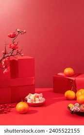 Tangerines, a plate of colorful gummy candy, a plate of jam and a red gift box are displayed on a lucky red background. Space for display and advertising.