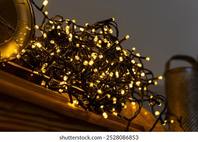 A tangle of warm white fairy lights rests on a wooden surface. The lights are closely clustered together, with some strands extending outward. - Powered by Shutterstock