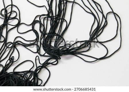 Tangled BlackThreads, A cluster of thin black cords lies in a loose, chaotic tangle against a clean white background.