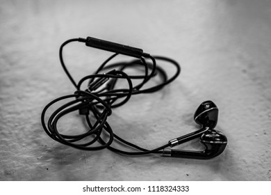  Tangled Earbuds Closeup On White Surface
