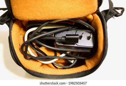 A Tangled Mess of Various Cords in a Travel Case