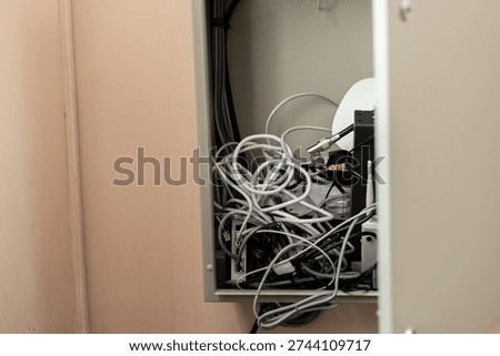 Tangled network and power cables in electrical cabinet. Disorganized router and cables in wall cabinet. 