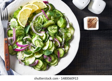 Tangy Refreshing Vegetarian Cucumber Salad Of Crunchy Sliced English Cucumbers, Pickled Red Onions, Fresh Dill, Mint Leaves With Vinaigrette Based Dressing, On A White Plate, Close-up, Copy Space