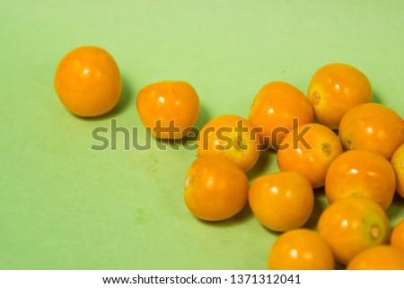 Tangy yellow gooseberries on a green background.