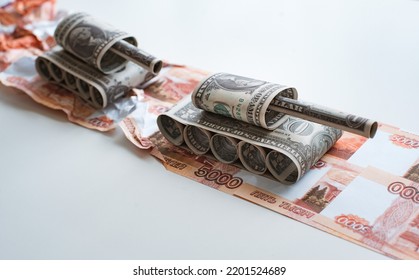 Tank Made Of Dollar Bills Rides On A Road Made Of Ruble Banknotes Bills. The Concept Of Arms Supply, Purchase And Sale Of Firearms, America Vs. Russia, Crumpled Money