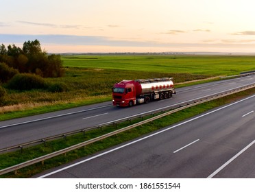 Tank Transport Of Liquid, Foodstuff. Metal Chrome Cistern Tanker For Food Transportation On Highway On Sunset Background. Soft Focus