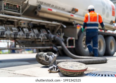 A Tanker Truck Driver Delivers Gasoline To A Gas Station