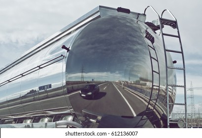 Tanker truck on the roads with a car reflected in the back.