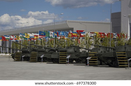 tanks stand in a row on the background of flags