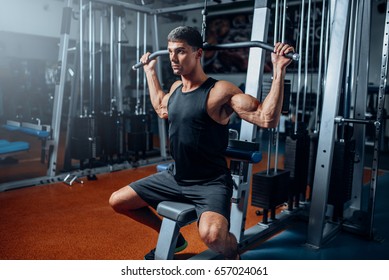 Tanned athlete workout on exercise machine in gym