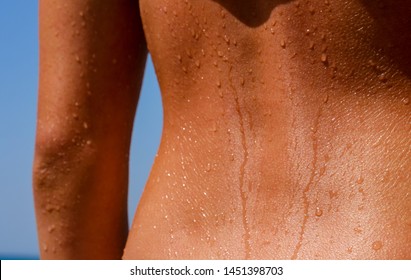 Tanned beautiful back of girl with water drops from bathing in the sea. Suitable for Fitness, Wellness, Medicine, Sports, Health, Cosmetics, Body care