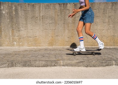 Tanned Child In Jeans Shorts Riding Longboard Skate In Modern Urban Space