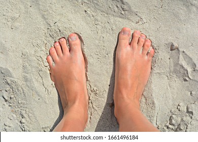 tanned feet without shoes on the hot white sand of Tunisia