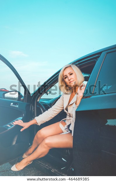 Tanned middle aged woman\
sitting inside the car, keeps auto door on parking. Right to drive\
Documents exam, modern life concept. Roadtrip travel vacation\
theme.