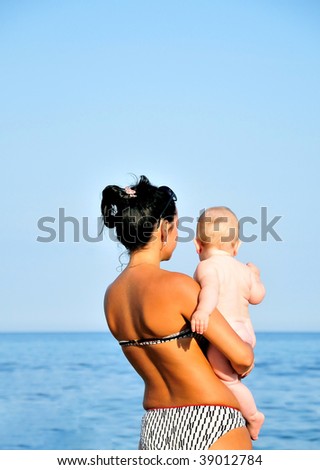 tanned mother showing  her  little baby Black sea