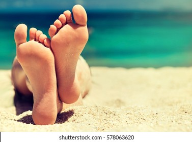 Tanned Well-groomed Feet Amid Tropical Turquoise Sea . Pedicure And Foot Spa .Care For The Heels And Soles Of The Feet .Foot Massage.