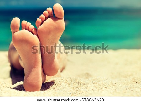Tanned well-groomed feet amid tropical turquoise sea . Pedicure and foot Spa .Care for the heels and soles of the feet .Foot massage.