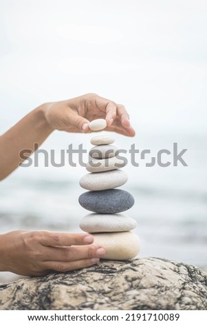 Tanned woman hands stacked pebble stones tower on sea beach relaxing harmony summer travel vacation. Female arms pillar formation peaceful balance pyramid spa spiritual gravel cobblestone at seaside