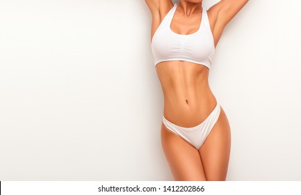 Tanned woman in top form, perfect body shape. Parts of woman body  in underwear, studio shoot.