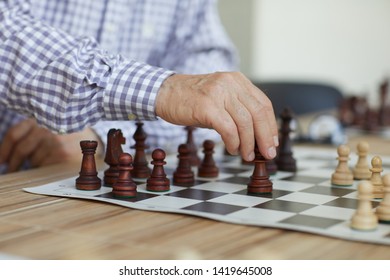 Tanned Wrinkled Hand Of Old Professional Grandmaster Making Decisive Chess Move During Intense Game