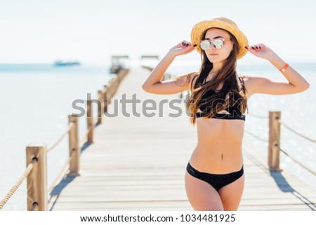 Tanning woman wearing sun hat at the sea on a wooden pier