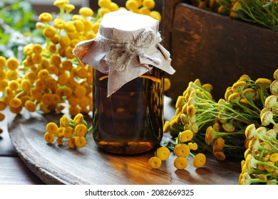 Tansy essential oil or extract in amber bottle with tanacetum  blossoms on wooden rustic background, closeup, natural cosmetics and naturopathy concept - Shutterstock ID 2082669325
