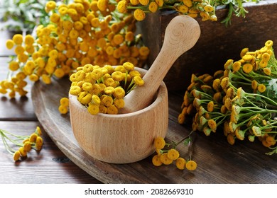 Tansy herb in a mortar with flowers on wood, herbal drink is good as anthelmintic, menstrual, kidney, rheumatism remedy , closeup, naturopathy and natural medicine concept