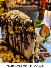 Tantalizing Kona Coffee Ice Cream Mudpie Topped With Nuts And Coconut Shavings Drizzled With Chocolate Sauce And An Oreo Cookie Crust.