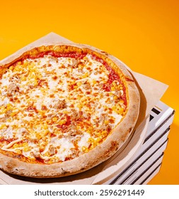 A tantalizing pizza sits on a stack of pizza boxes, showcasing a golden crust topped with melted cheese, chunks of sausage, and sweet corn, all against a vibrant yellow backdrop.
