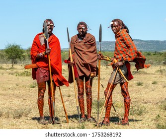 TANZANIA, EAST AFRICA - AUGUST 12, 2018: Three young Masai warriors in traditional clothes and weapons are standing in the savannah. Tanzania, East Africa, August 12, 2018.