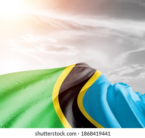Tanzania national flag cloth fabric waving on beautiful sky background.