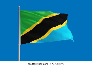 Tanzania national flag waving in the wind on a deep blue sky. High quality fabric. International relations concept.