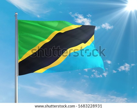 Tanzania national flag waving in the wind against deep blue sky. High quality fabric. International relations concept.