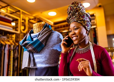 tanzanian woman with snake print turban over hear working in fabrics shop calling to client by smartphone