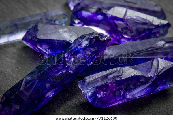 Tanzanites\
and raw crystal gems concept with closeup of a bunch of blue and\
purple uncut tanzanite or sapphire\
crystals
