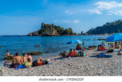 Taormina, Italy - July 25, 2020 - Swimmers And People Sunbathing On Isola Bella Beach In Sicily