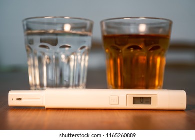 Tap drinking water quality control tester in front of two glasses of pure and dirty water for TDS Total dissolved solids test