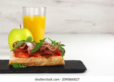 Tapas With Spanish Hamon Or Bruschetta With Italian Proscuitto, Orange Juice And An Apple