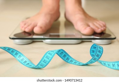 Tape in front of woman standing on floor scales indoors. Overweight problem - Shutterstock ID 1490713412