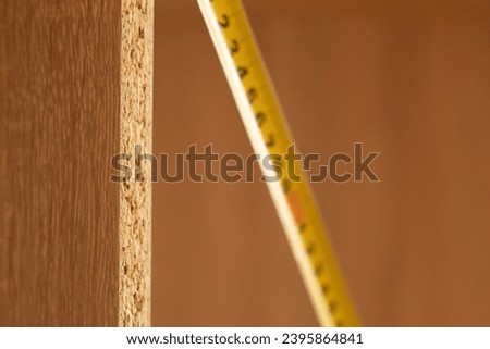 Tape measure and the end of a wooden board. Measurement in centimeters and millimeters. Furniture assembly
