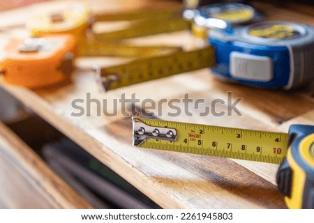 Tape measure with linear-measured markings on wooden background, DIY maker and woodworking concept. selective focus