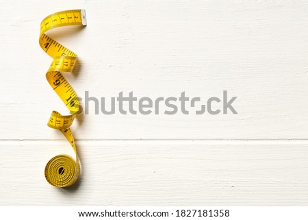 Tape measure sewing tool over white wooden table background with copy space, top view flat lay from above