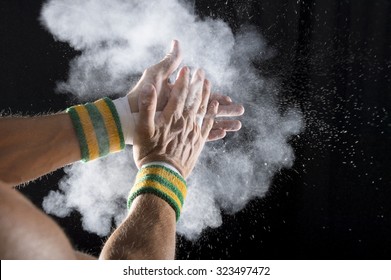 Taped Hands Of Gymnast Clapping White Chalk Powder Into A Cloud Against Dark Background