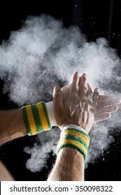 Taped Hands Of Gymnast Clapping White Chalk Powder Into A Cloud Against Dark Background